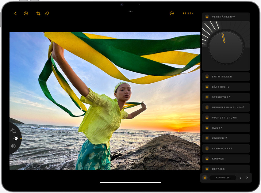 Ein iPad Air im Querformat, der Bildschirm zeigt das Foto eines Mädchens, das gelbe und grüne Bänder hält und vor einem Sonnenuntergang am Meer steht