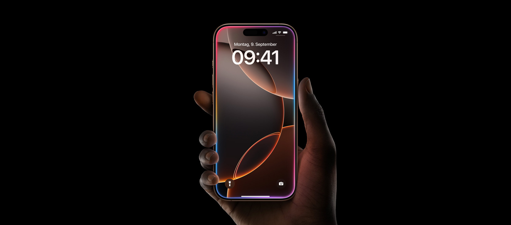 Eine Hand hält das iPhone 16 Pro in Titan Wüstensand, All‑Screen Display, Dynamic Island oben in der Mitte, gerundete Ecken