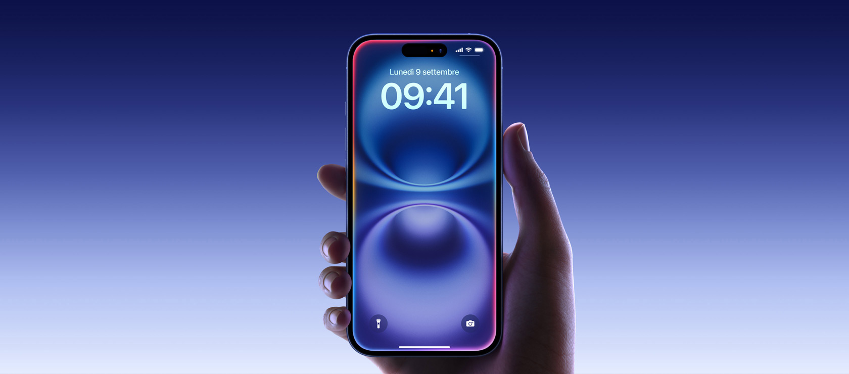 Una mano che tiene un iPhone 16 blu oltremare, display all-screen con Dynamic Island al centro verso il bordo superiore, angoli arrotondati