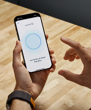 يحمل أحد مستخدمي سماعات AirPods Pro 2‏ جهاز iPhone أثناء استخدام ميزة اختبار السمع الجديدة