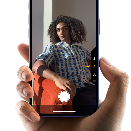 صورة ليد تحمل iPhone 16 بلون أزرق عمق البحر مع إبهام يُمرّر فوق زر التحكم في الكاميرا لضبط عمق المجال
