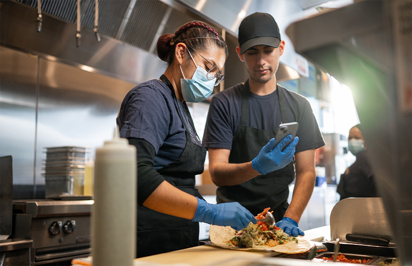Una empleada aprende a enrollar un burrito al estilo Señor Sisig.