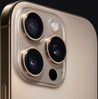 Close-up view of back of iPhone 16 Pro in color Desert Titanium showing cameras and side button.