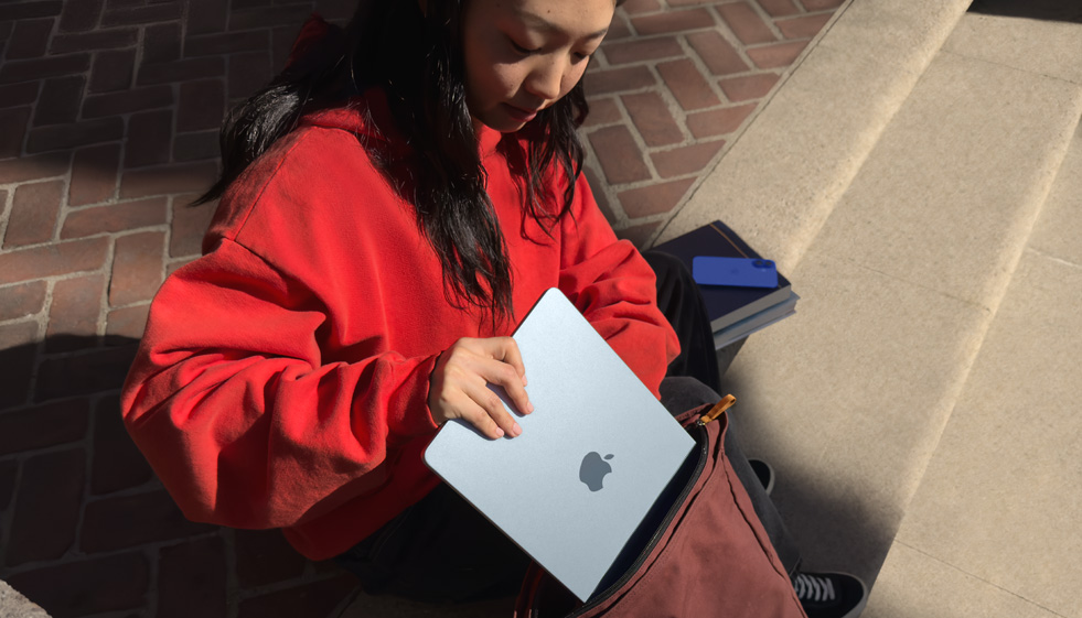 طالبة تضع جهاز MacBook Air في حقيبة ظهرها